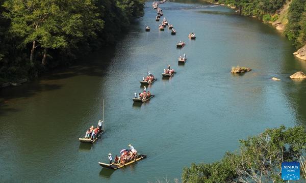 Tourists enjoy the view on bamboo rafts along the Jiuqu Stream in Wuyi Mountain, southeast China's Fujian Province, Oct. 1, 2023. People across the country enjoy themselves in various way on the first day of the National Day holiday. (Photo by Qiu Ruquan/Xinhua)